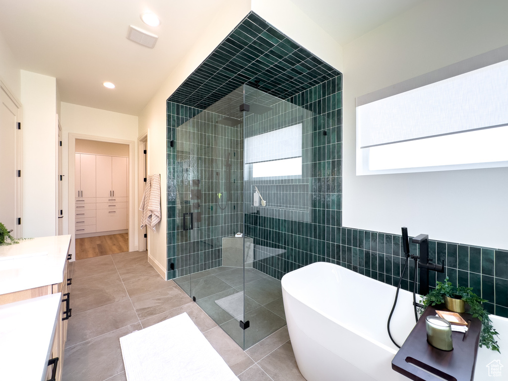 Full bath with a stall shower, a soaking tub, vanity, recessed lighting, and tile patterned floors