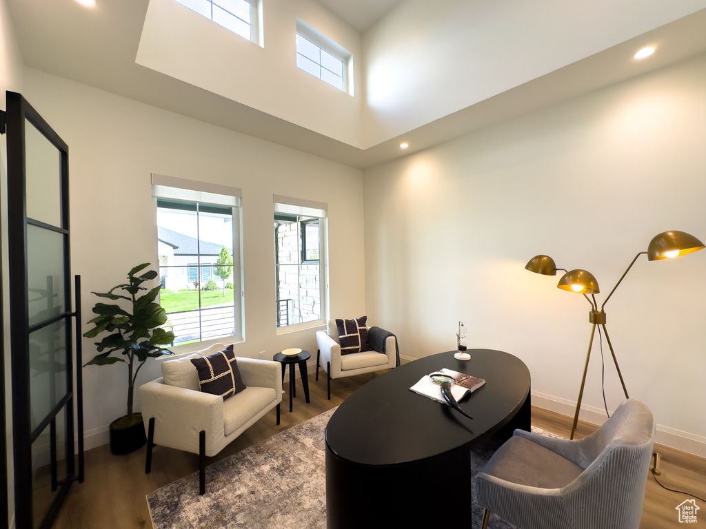 Living room featuring wood finished floors, baseboards, recessed lighting, and a towering ceiling