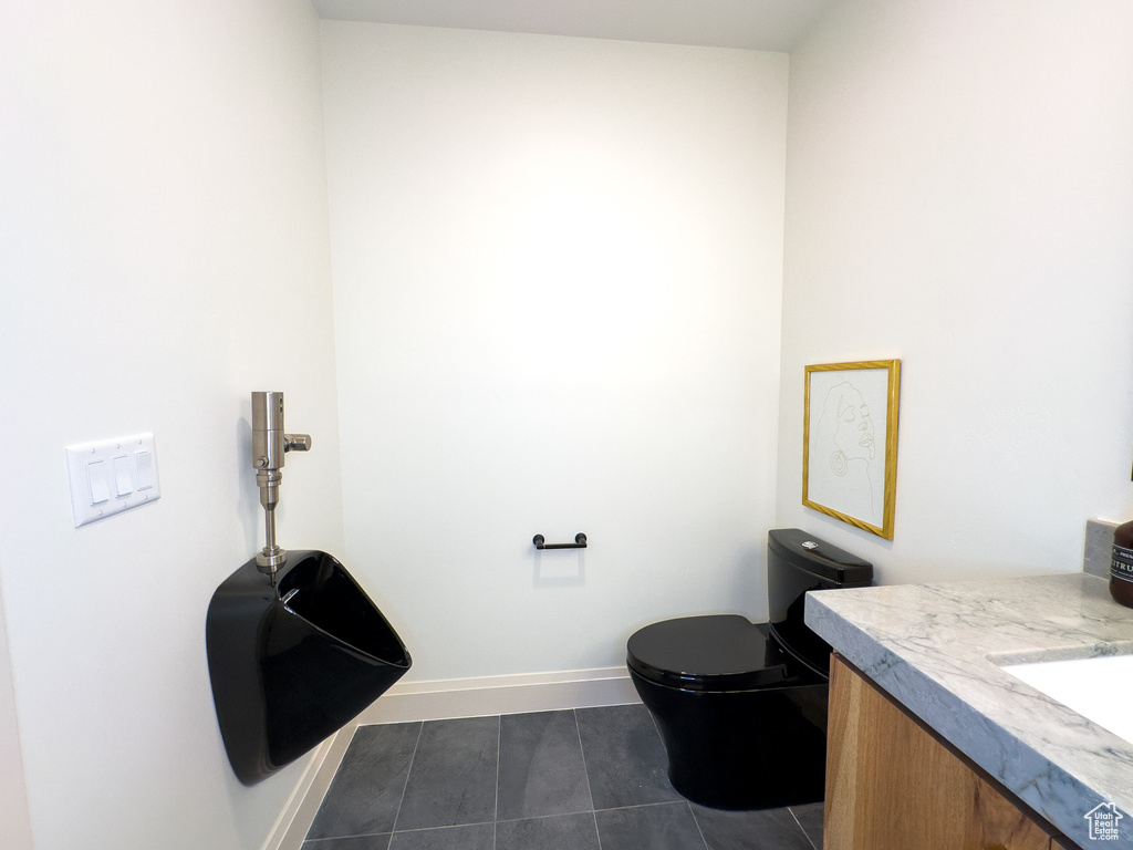 Bathroom featuring vanity, toilet, tile patterned flooring, and baseboards