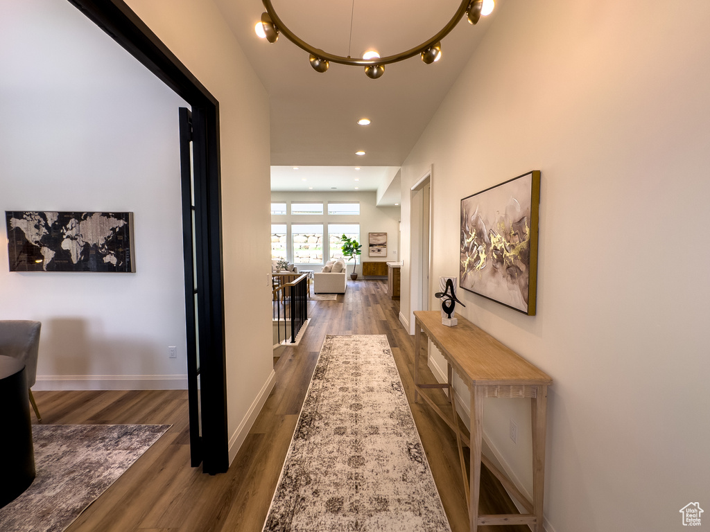 Hall with wood finished floors, recessed lighting, a chandelier, and baseboards