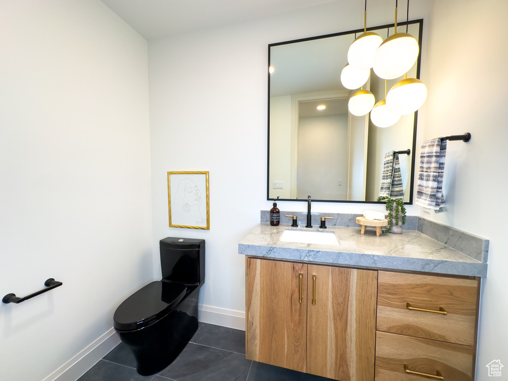 Half bath featuring tile patterned flooring, vanity, baseboards, and toilet