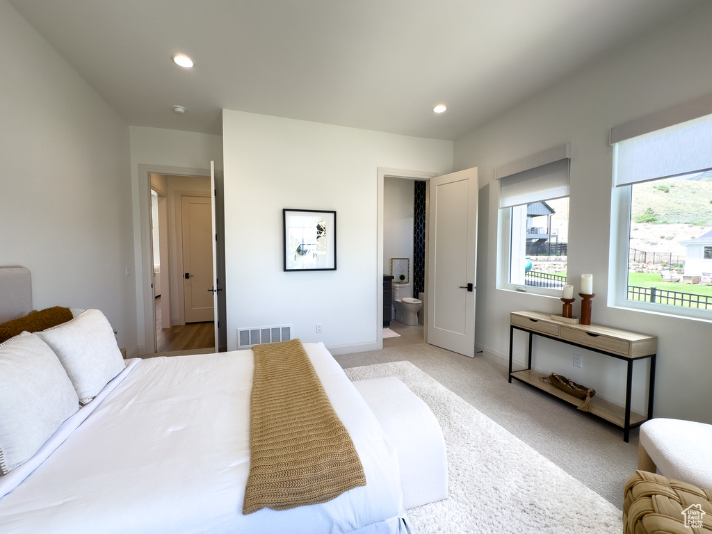 Bedroom featuring recessed lighting, baseboards, light colored carpet, and connected bathroom