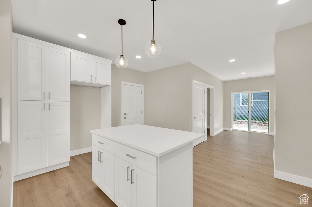Kitchen featuring light wood-style flooring, baseboards, white cabinets, recessed lighting, and decorative light fixtures
