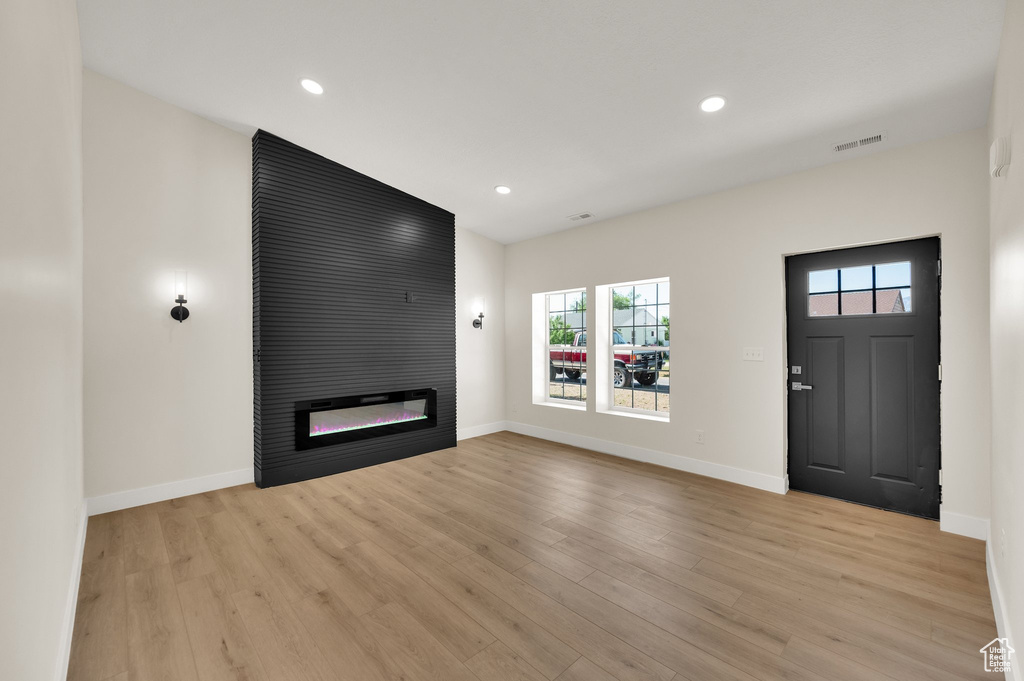 Unfurnished living room featuring a fireplace, plenty of natural light, baseboards, light wood-style flooring, and recessed lighting
