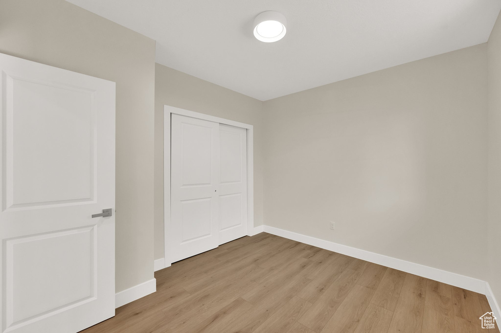 Unfurnished bedroom with baseboards, light wood-style floors, and a closet