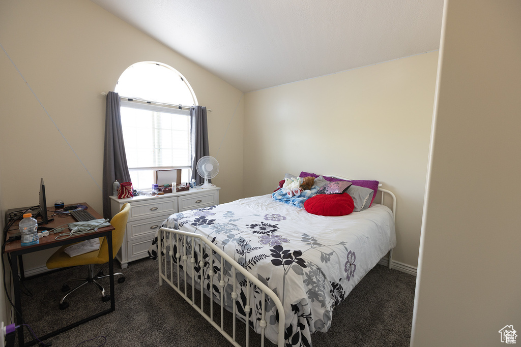 Bedroom with dark carpet and vaulted ceiling