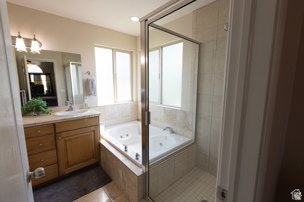 Bathroom featuring a tub with jets, vanity, a stall shower, and tile patterned flooring