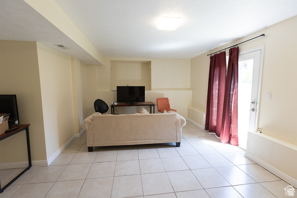 Living area with healthy amount of natural light, light tile patterned floors, and baseboards