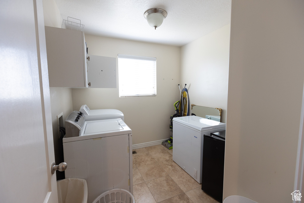 Laundry room featuring washer and dryer, cabinet space, and baseboards