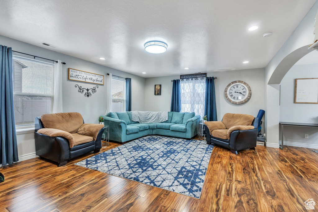 Living room featuring arched walkways, wood finished floors, baseboards, and recessed lighting