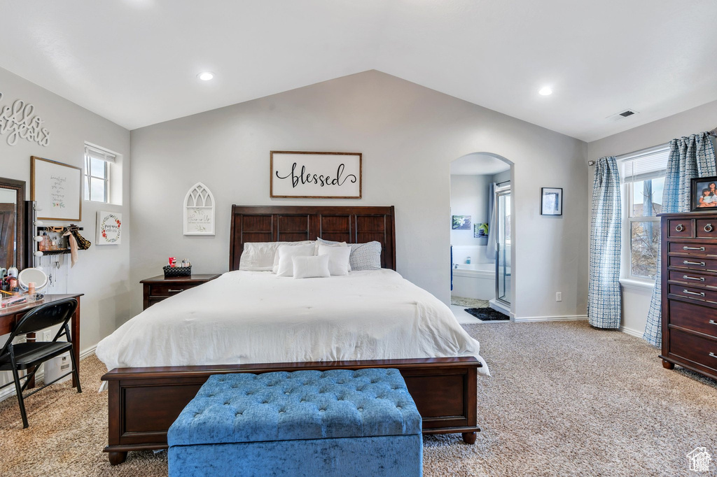 Carpeted bedroom featuring arched walkways, vaulted ceiling, baseboards, recessed lighting, and ensuite bath