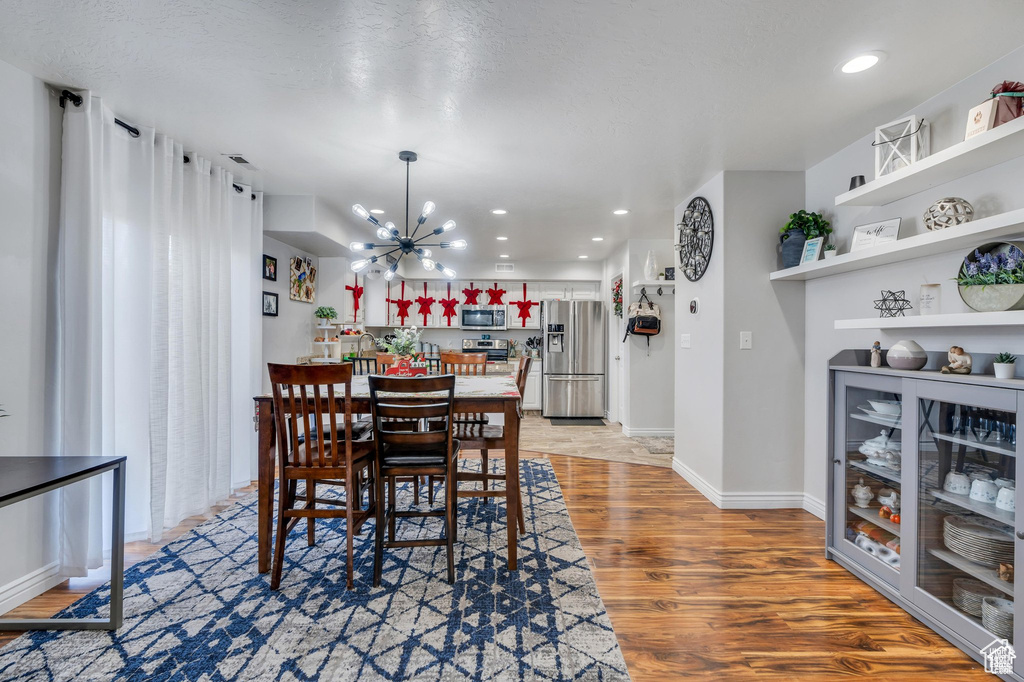 Dining room featuring a chandelier, light wood-type flooring, recessed lighting, and baseboards