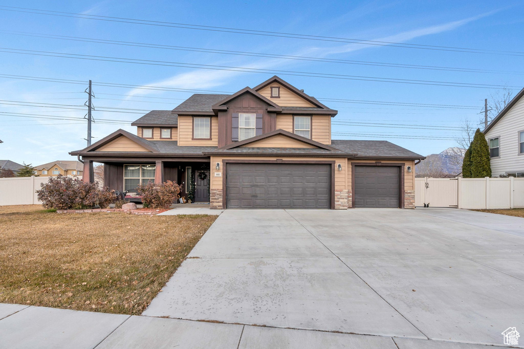 View of front facade featuring driveway, an attached garage, covered porch, stone siding, and board and batten siding