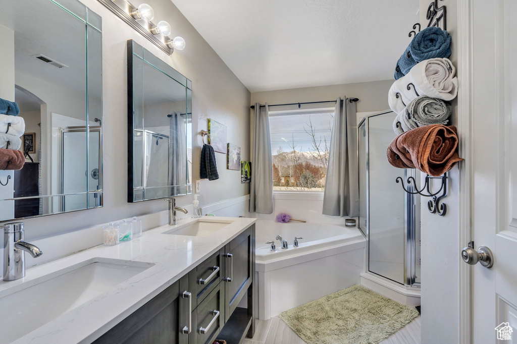 Full bathroom featuring a shower stall, a bath, and double vanity