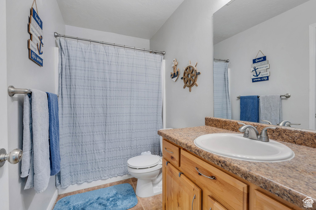 Bathroom featuring vanity, toilet, tile patterned floors, and curtained shower