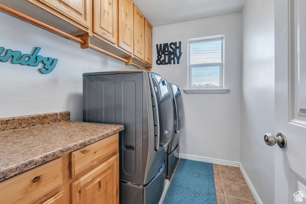 Laundry area featuring washer and clothes dryer, cabinet space, baseboards, and light tile patterned floors