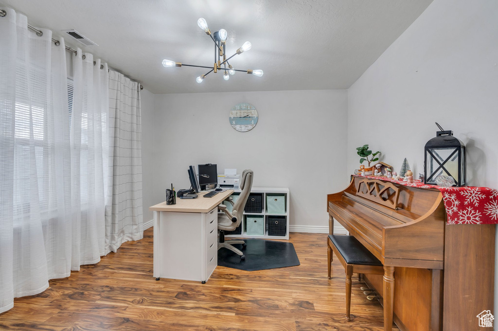 Home office featuring a chandelier, wood finished floors, and baseboards