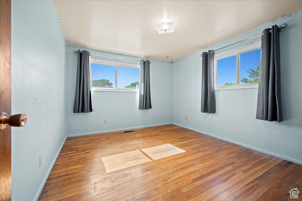 Spare room featuring plenty of natural light, wood-type flooring, and baseboards