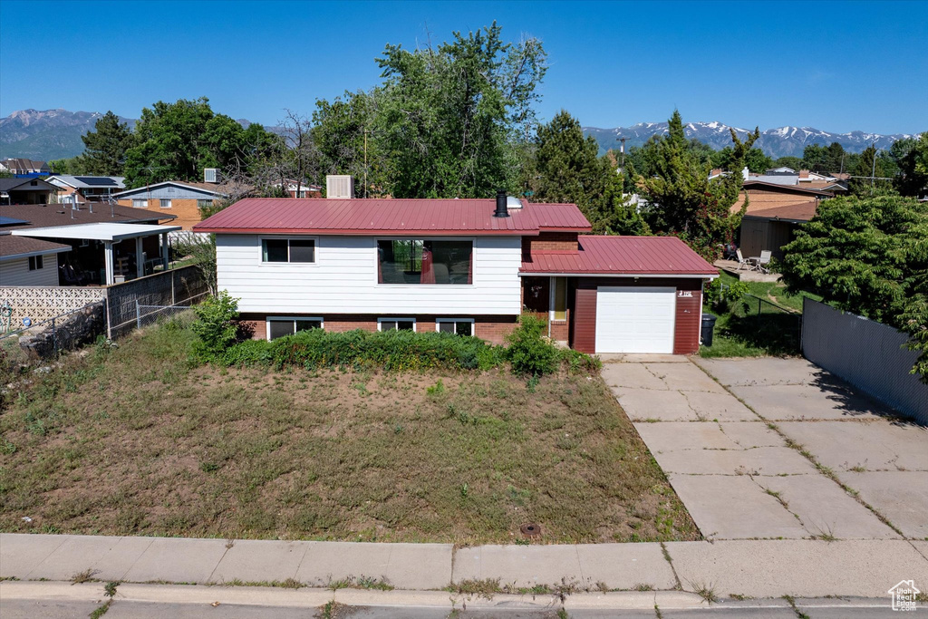 View of front facade with an attached garage, driveway, a mountain view, and metal roof