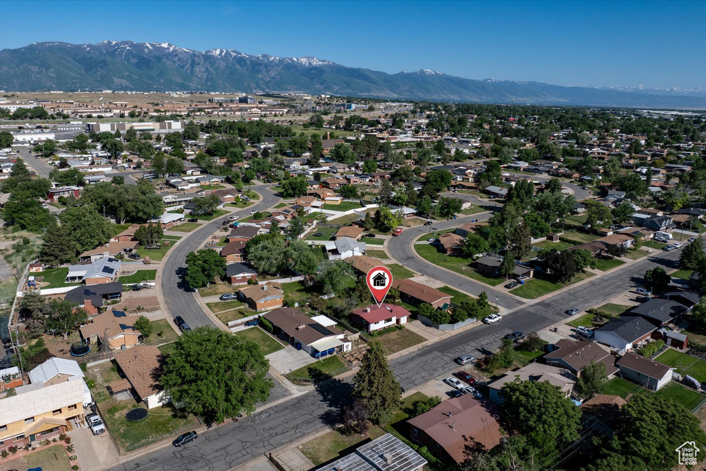Aerial view of property and surrounding area featuring a mountainous background and nearby suburban area