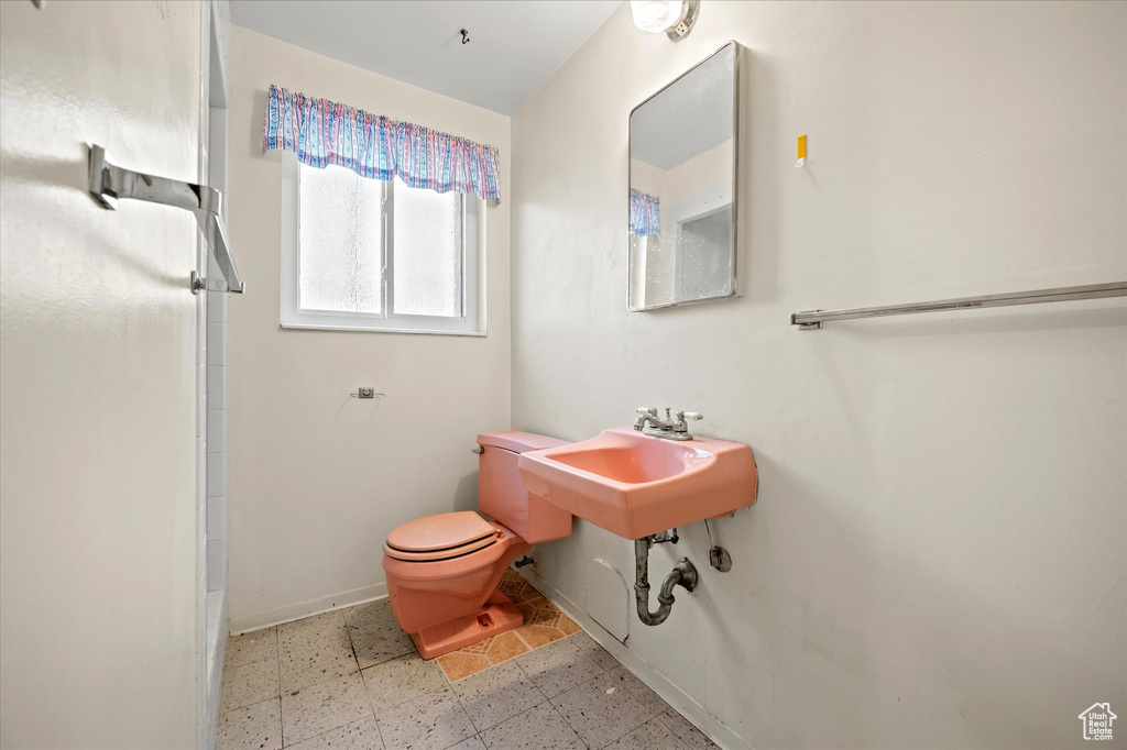 Full bathroom with toilet, a shower, baseboards, and a sink
