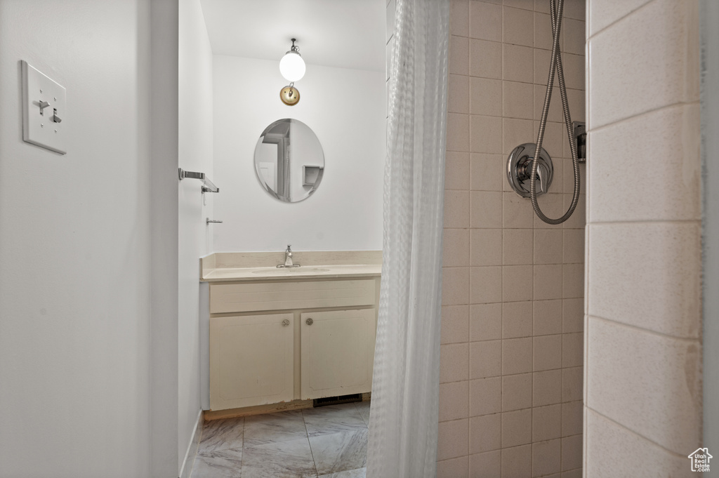 Bathroom with a tile shower, vanity, and marble finish floors