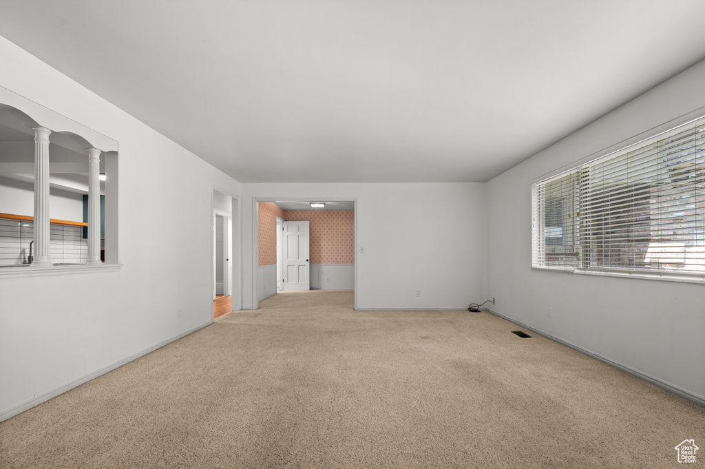 Carpeted empty room featuring decorative columns and baseboards