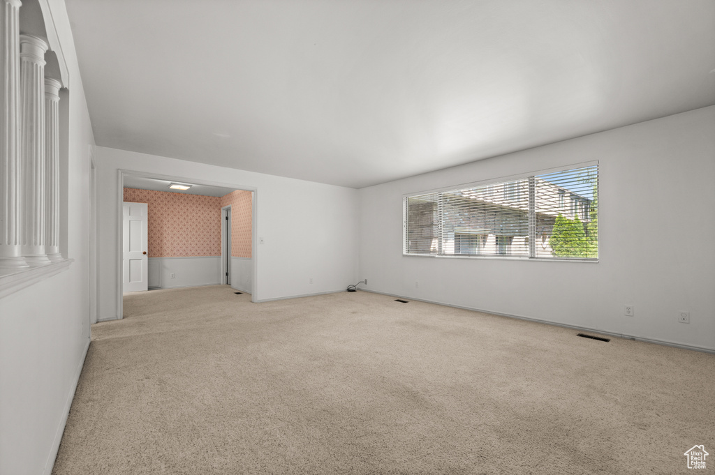 Empty room featuring wallpapered walls, light colored carpet, and baseboards