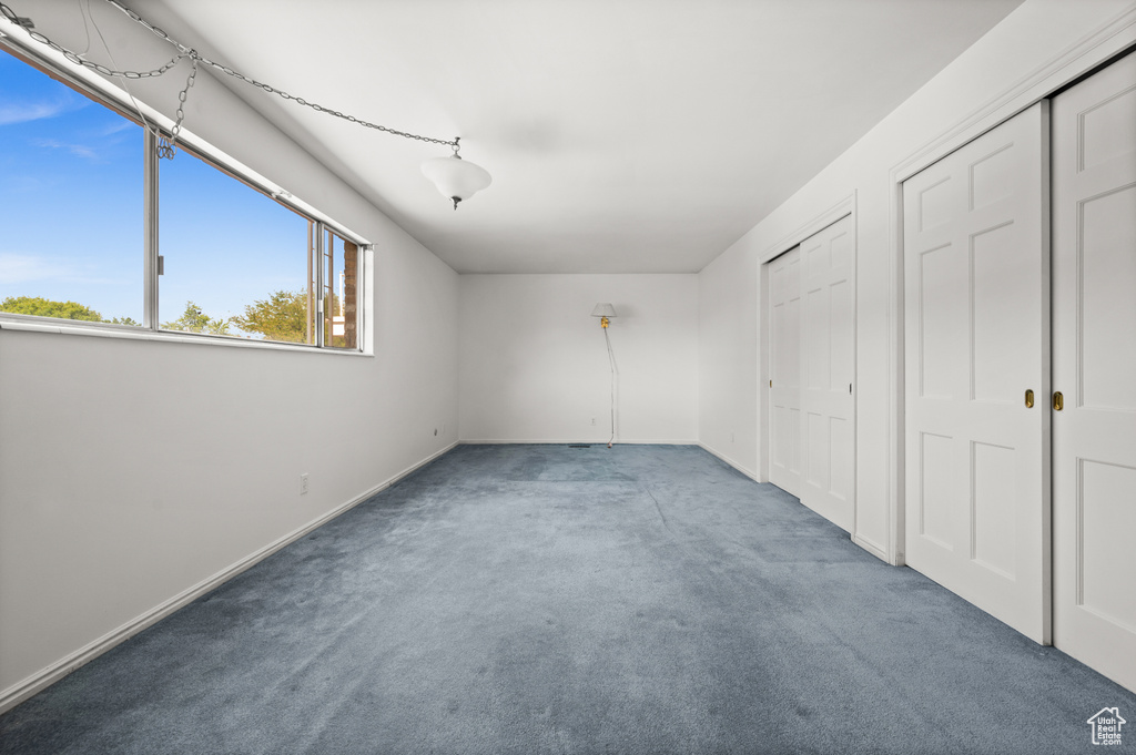 Unfurnished bedroom featuring carpet, baseboards, and two closets