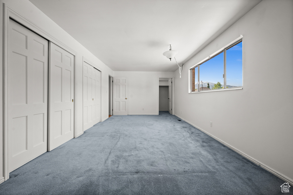 Unfurnished bedroom featuring carpet floors, two closets, and baseboards