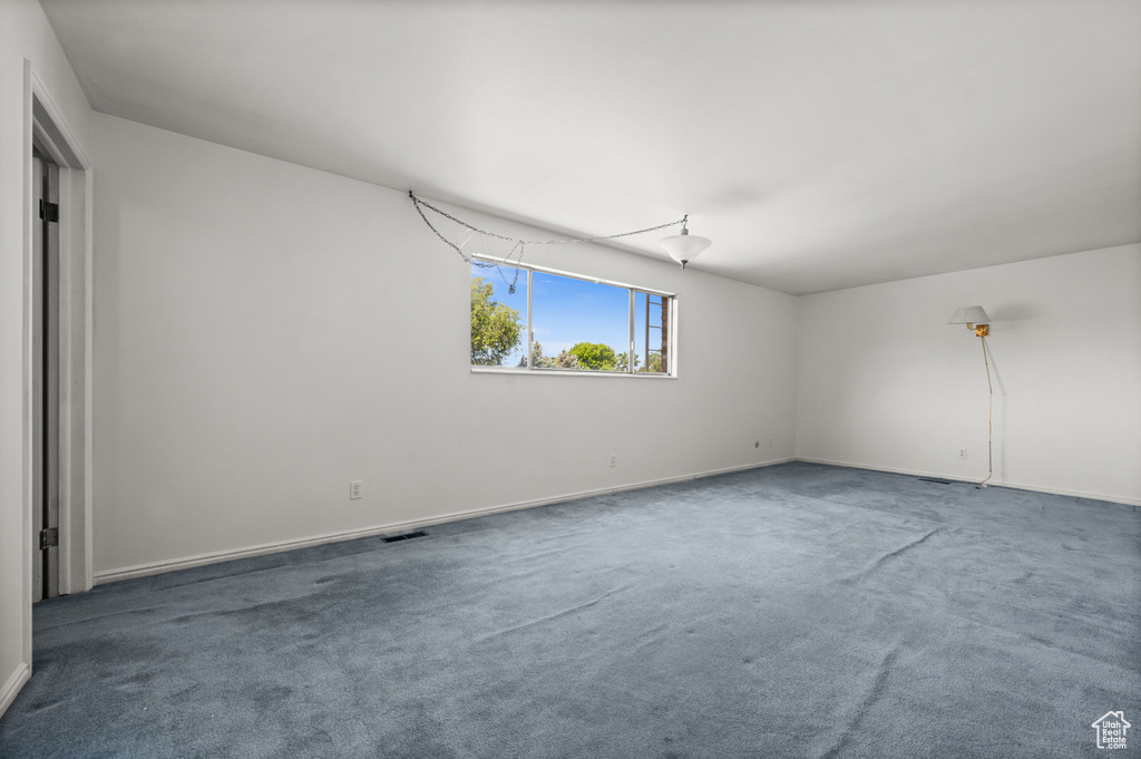 Carpeted spare room featuring baseboards
