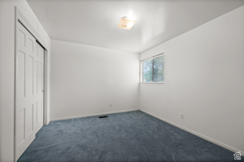 Unfurnished bedroom featuring dark carpet, a closet, and baseboards