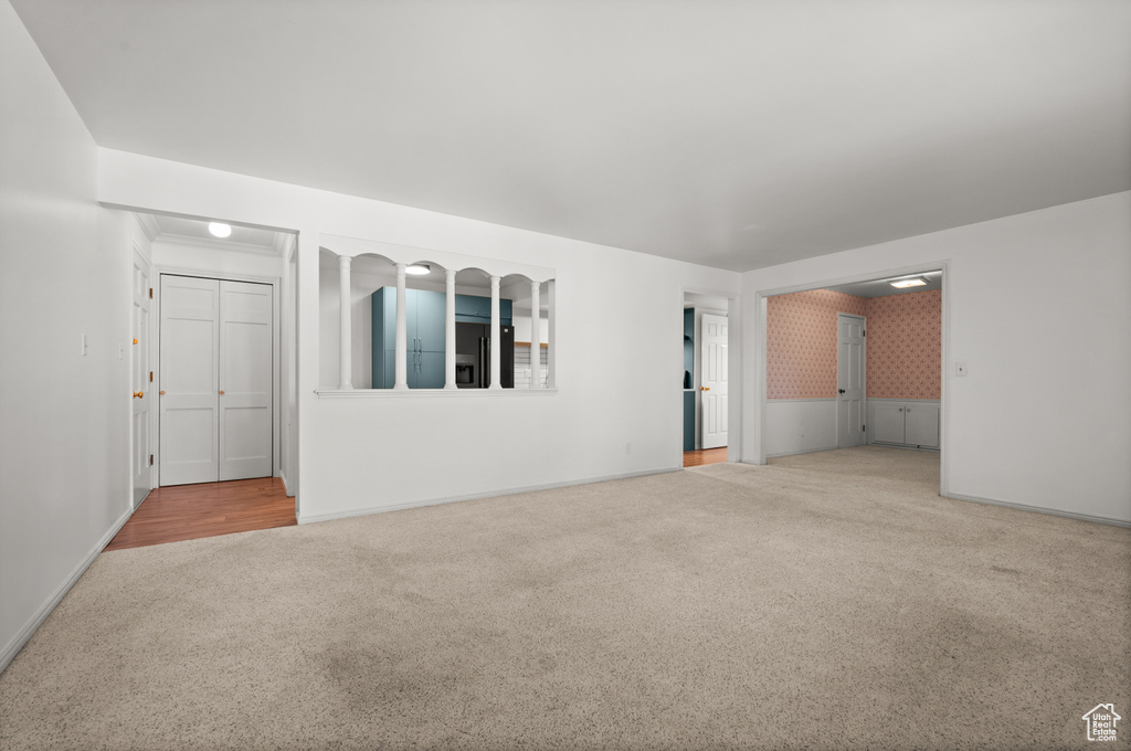 Unfurnished living room featuring carpet flooring, baseboards, and a wainscoted wall