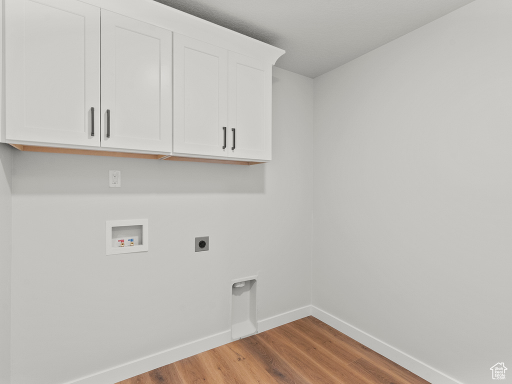 Laundry area featuring hookup for an electric dryer, cabinet space, hookup for a washing machine, and wood finished floors