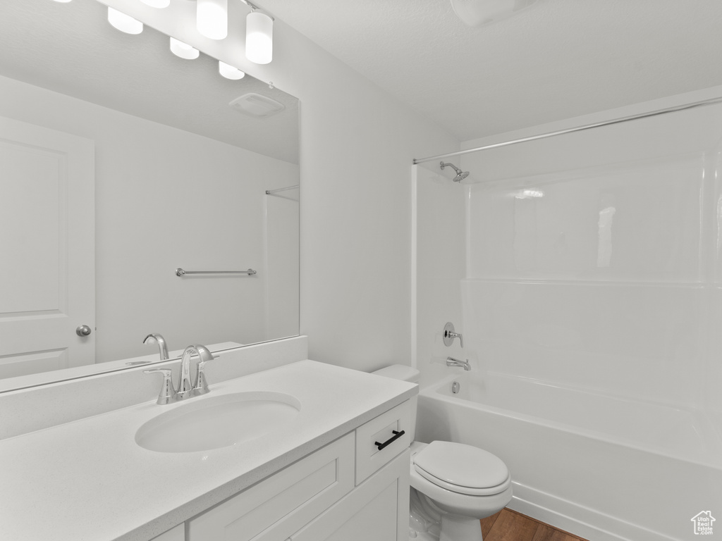 Full bath with vanity, shower / bath combination, and wood finished floors
