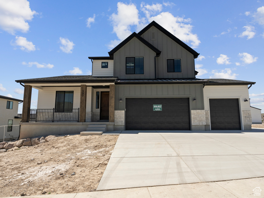 View of front facade with a porch, board and batten siding, concrete driveway, and a garage