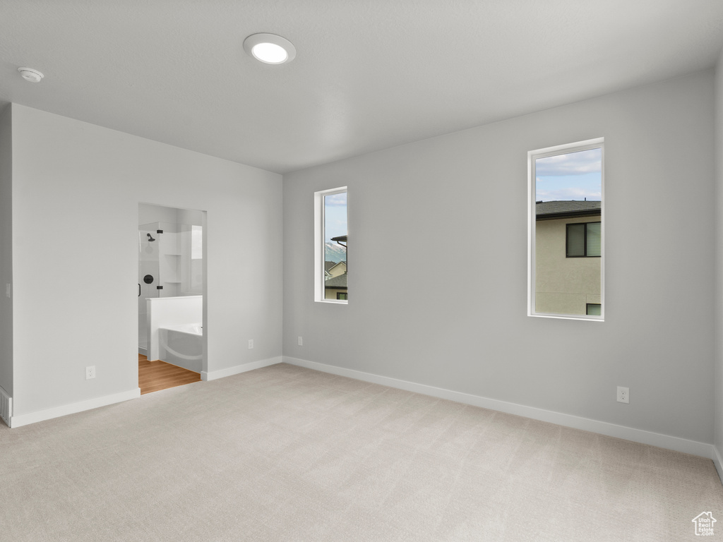 Unfurnished bedroom with light carpet and ensuite bath