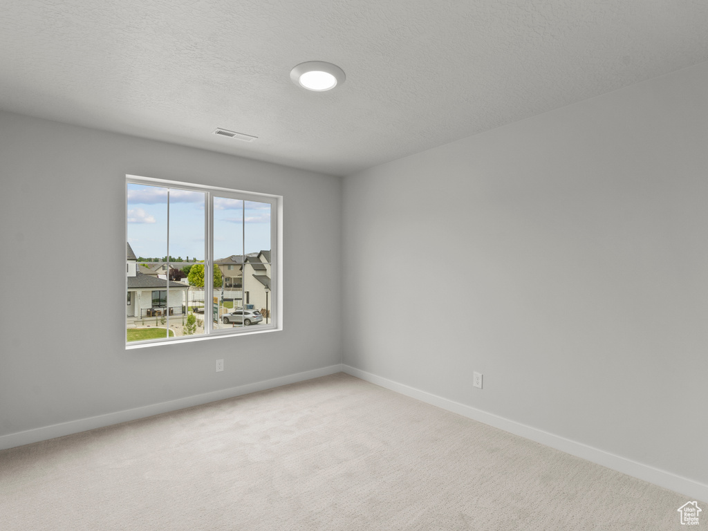 Empty room with carpet flooring and a textured ceiling