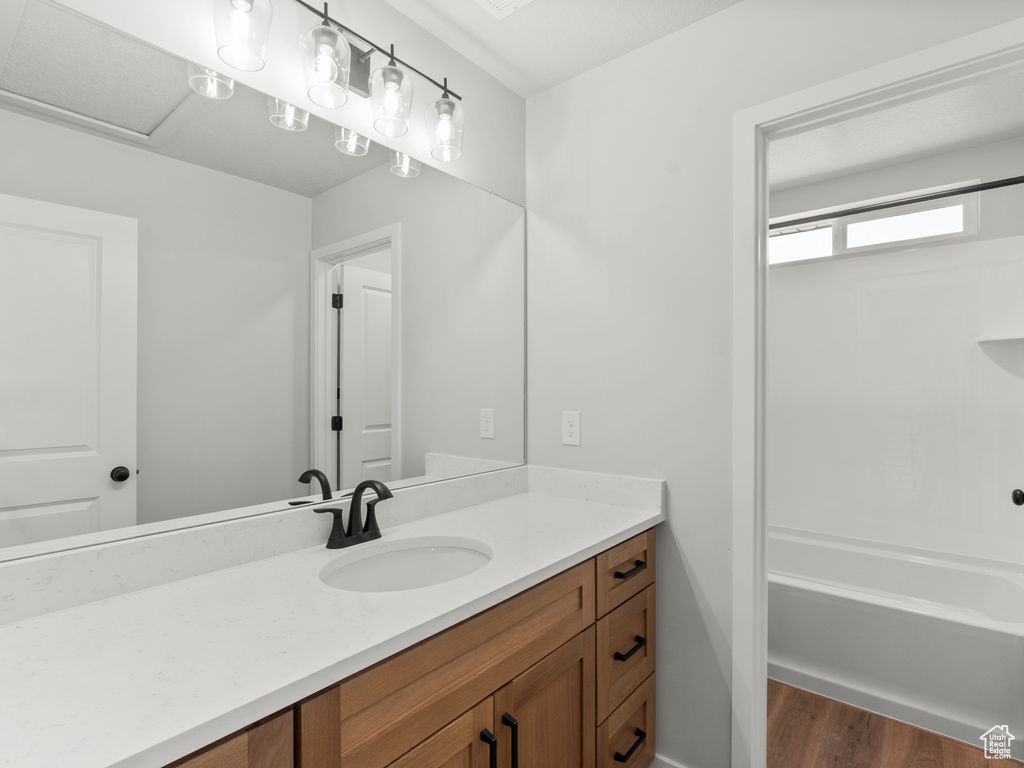 Bathroom with vanity, wood finished floors, and  shower combination