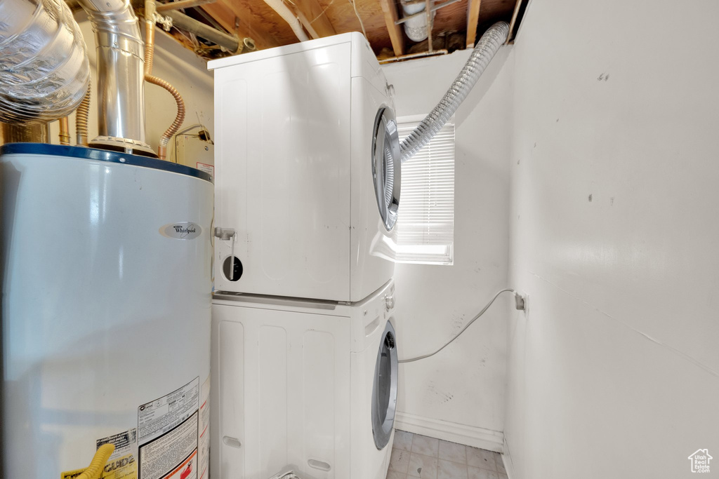 Washroom featuring stacked washer / dryer, water heater, and baseboards