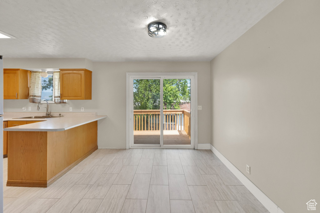 Kitchen featuring a sink, light countertops, a textured ceiling, a peninsula, and wood tiled floors