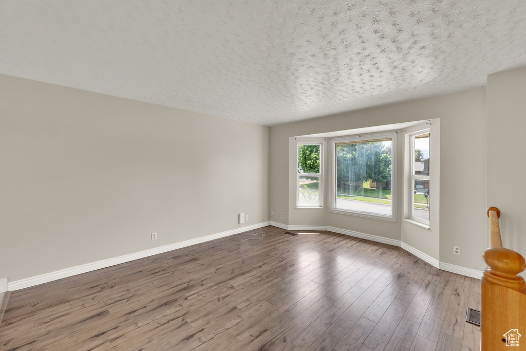 Spare room featuring baseboards, wood finished floors, and a textured ceiling