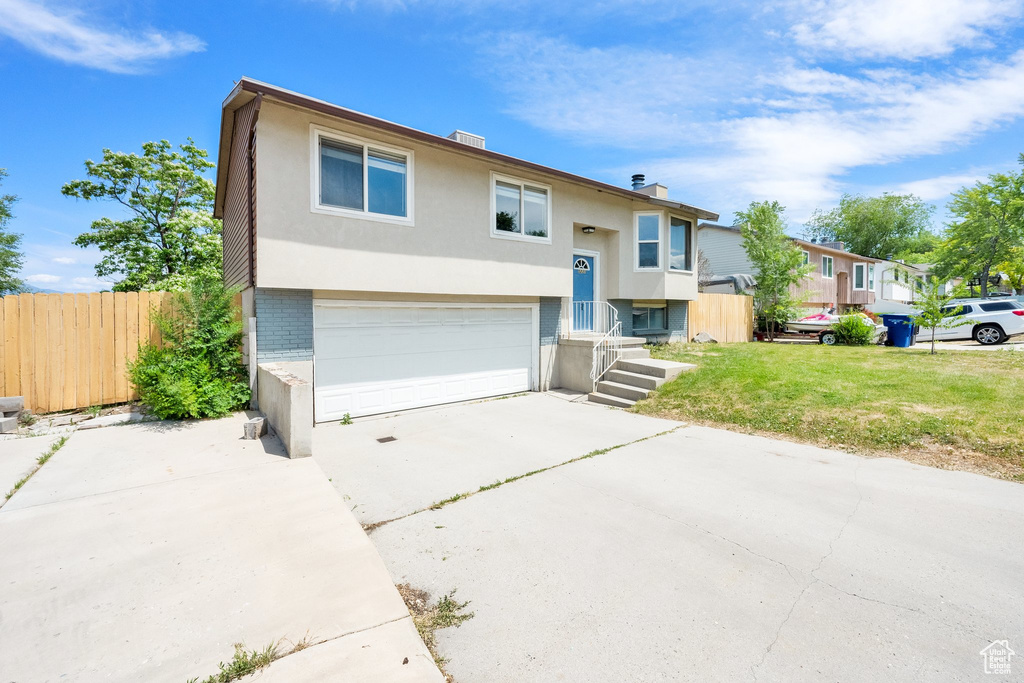 Bi-level home with an attached garage, concrete driveway, and stucco siding