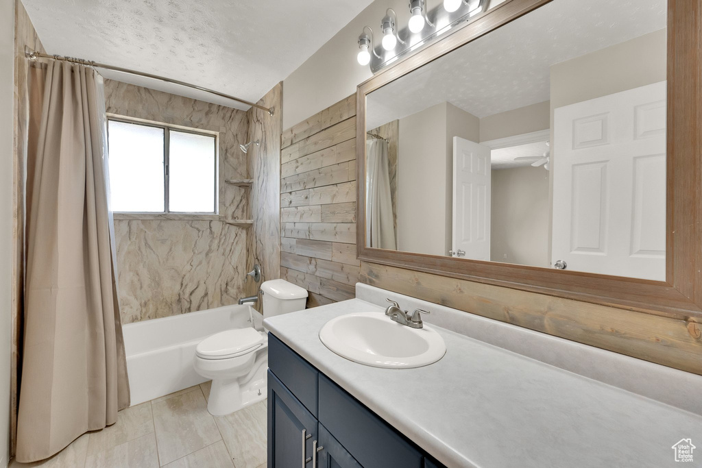 Bathroom with vanity, shower / tub combo, toilet, and a textured ceiling