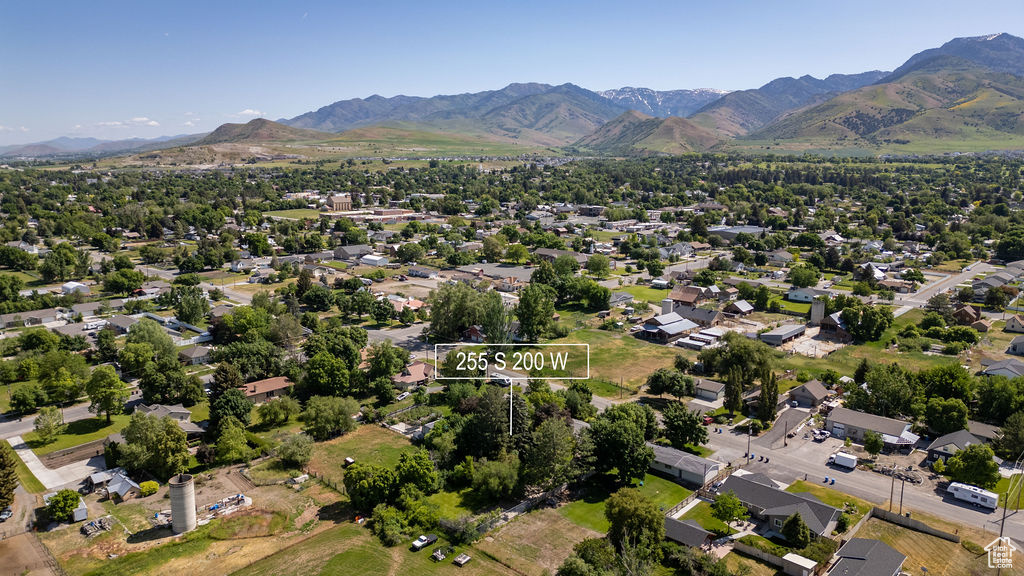 Aerial view of property and surrounding area featuring mountains and nearby suburban area