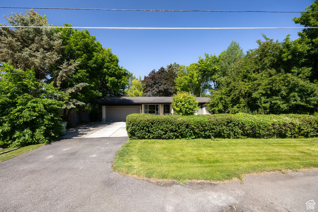 View of front of home with a garage, driveway, and a front lawn