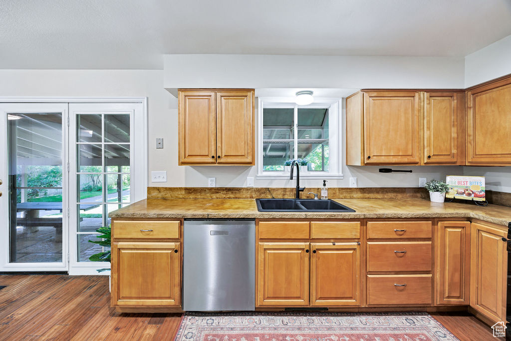 Kitchen with dishwasher, a sink, and wood finished floors