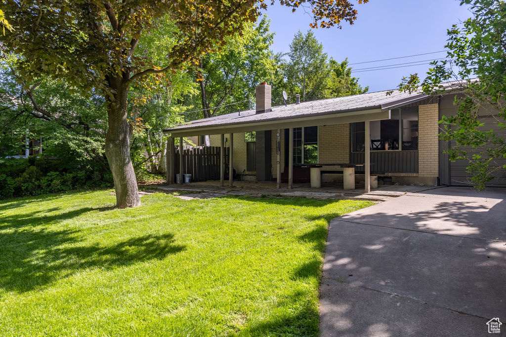 Ranch-style house with brick siding, a front yard, a chimney, and concrete driveway