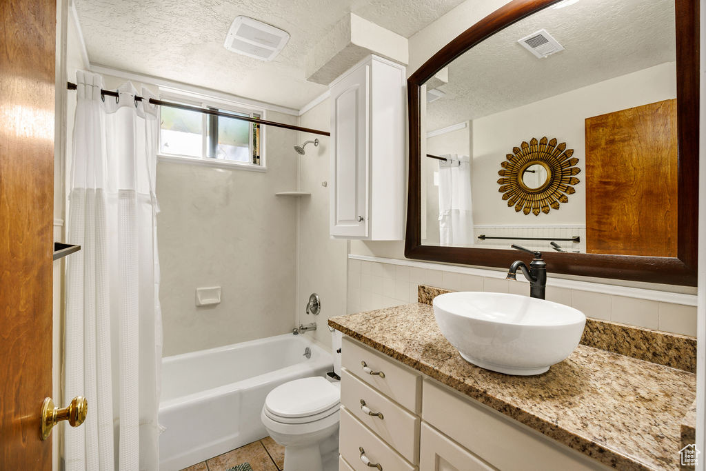 Full bathroom with a textured ceiling, shower / tub combo with curtain, vanity, tasteful backsplash, and toilet