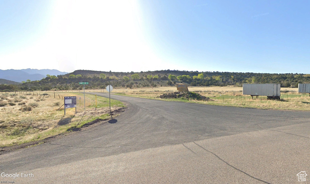 View of asphalt street with a mountain view, traffic signs, and a view of countryside